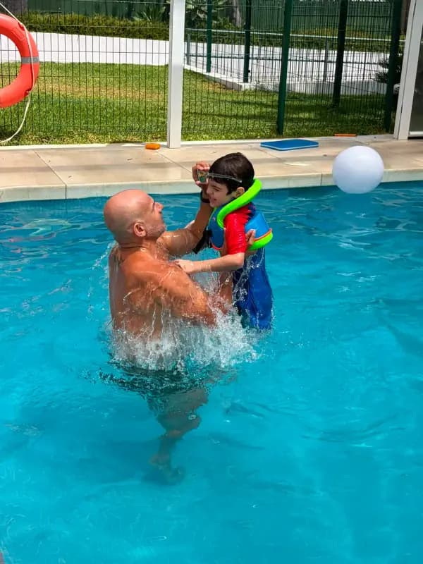 Niño recibiendo apoyo individual durante una clase de natación adaptada en la piscina de Casa Ángeles en Marbella.