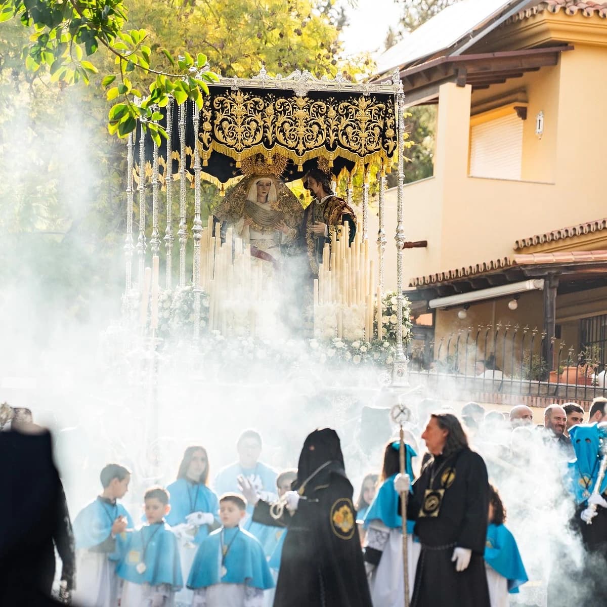 Procesión del Calvario en Marbella durante el Jueves Santo, con el trono de María Santísima del Calvario y San Juan Evangelista entre incienso, cirios y cortejo cofrade a su paso por la ciudad.