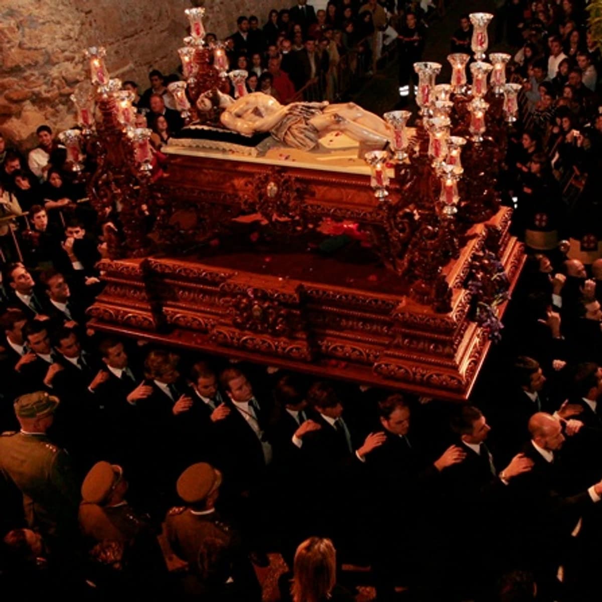 Procesión del Santo Sepulcro en Marbella durante el Viernes Santo, con el Cristo Yacente sobre un trono oscuro rodeado de portadores, legionarios y público en una escena nocturna de gran solemnidad.