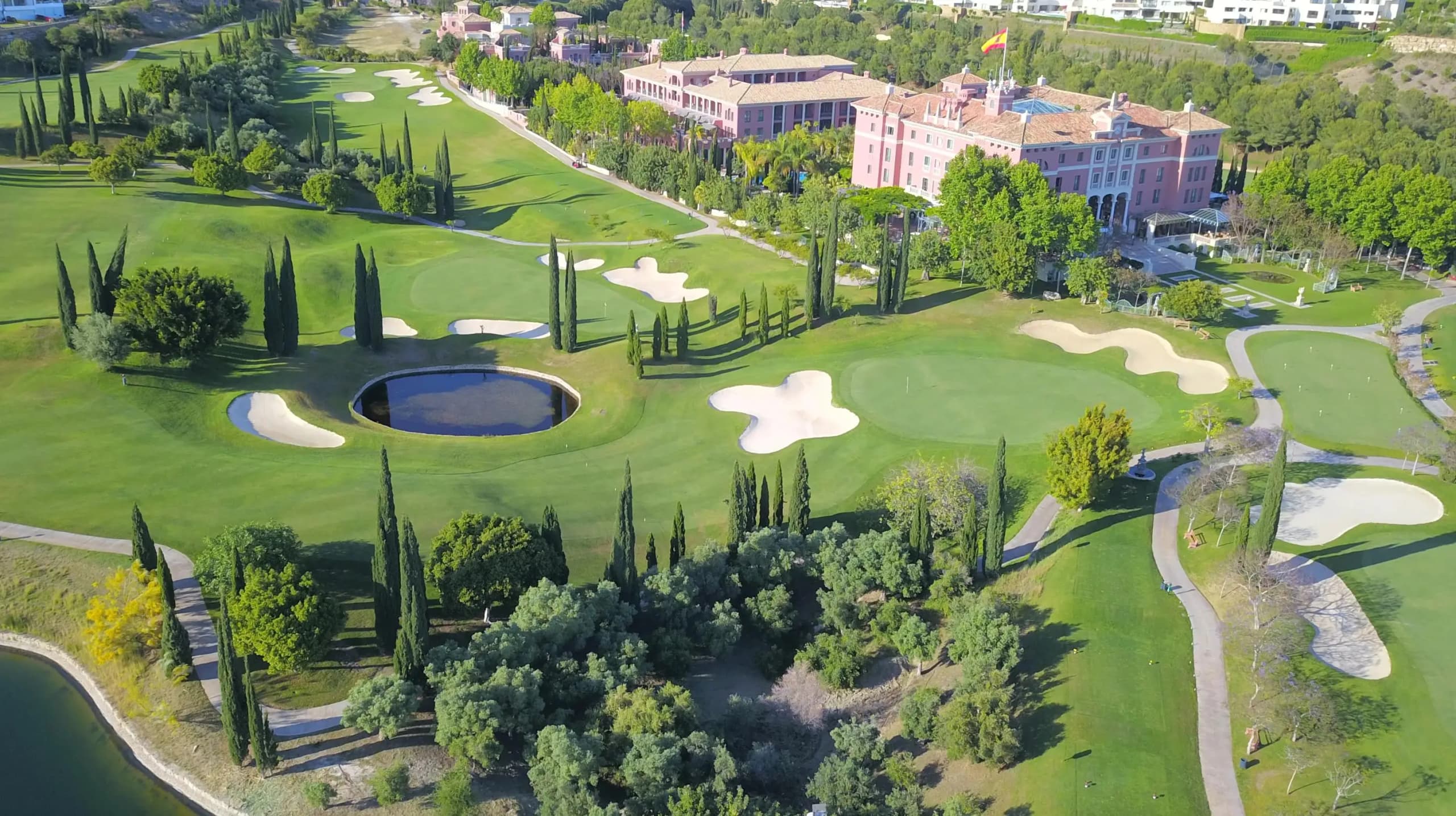 Vista aérea del campo de golf Villa Padierna en Marbella, Costa del Sol, con greens perfectamente cuidados, bunkers de arena, cipreses y el hotel Villa Padierna Palace al fondo.