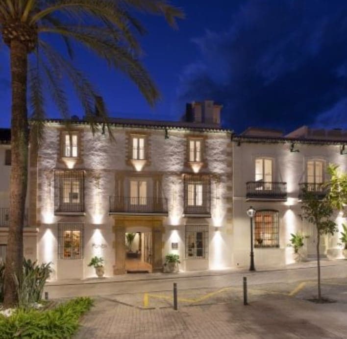 Exterior nocturno del hotel La Fonda Heritage en la Plaza Santo Cristo del casco antiguo de Marbella, con iluminación arquitectónica.